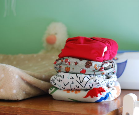 Stack of colorful cloth diapers next to a home baby-changing station.